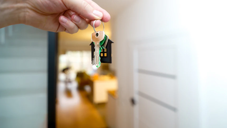 A person holding a set of house keys in front of a front door at handover.